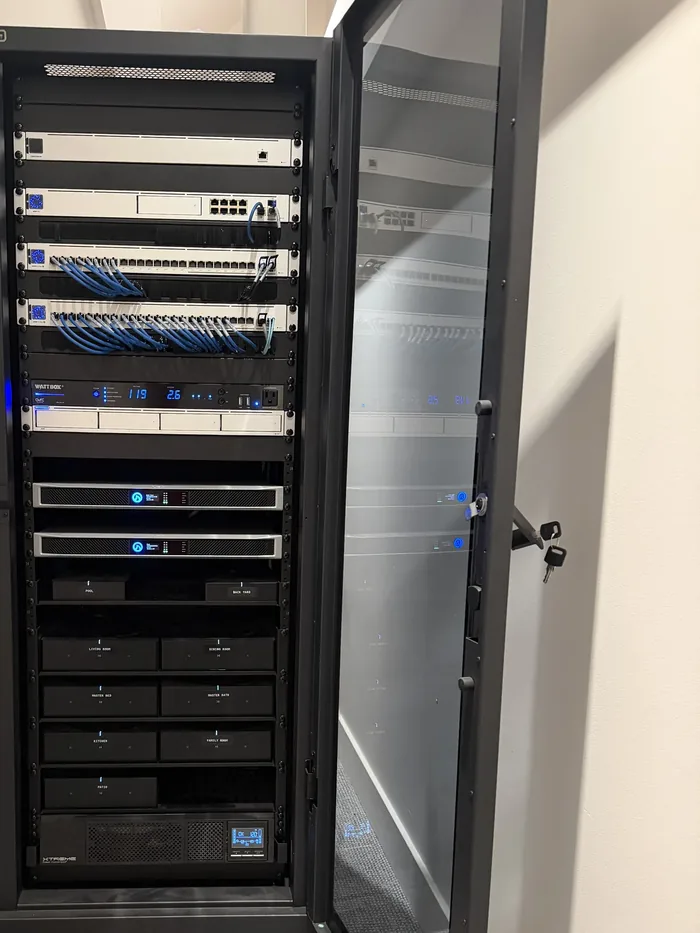 Finished equipment rack with dressed cabling and amplifiers labeled by zone